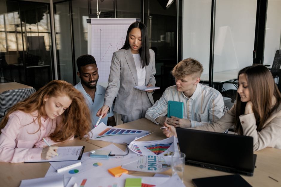 Colleagues reviewing business notes and charts at a table, illustrative stock photo