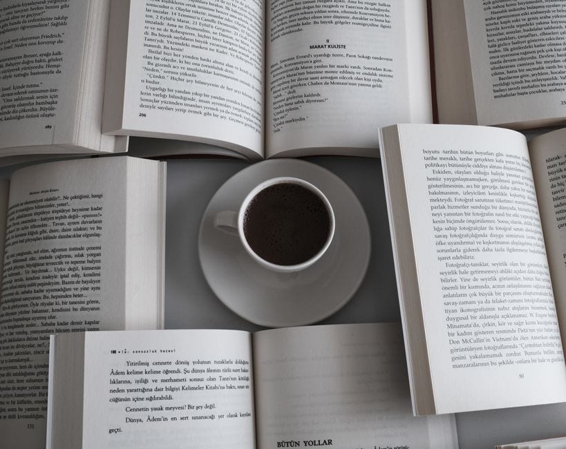 Illustrative stock photo of open books beside a cup of coffee