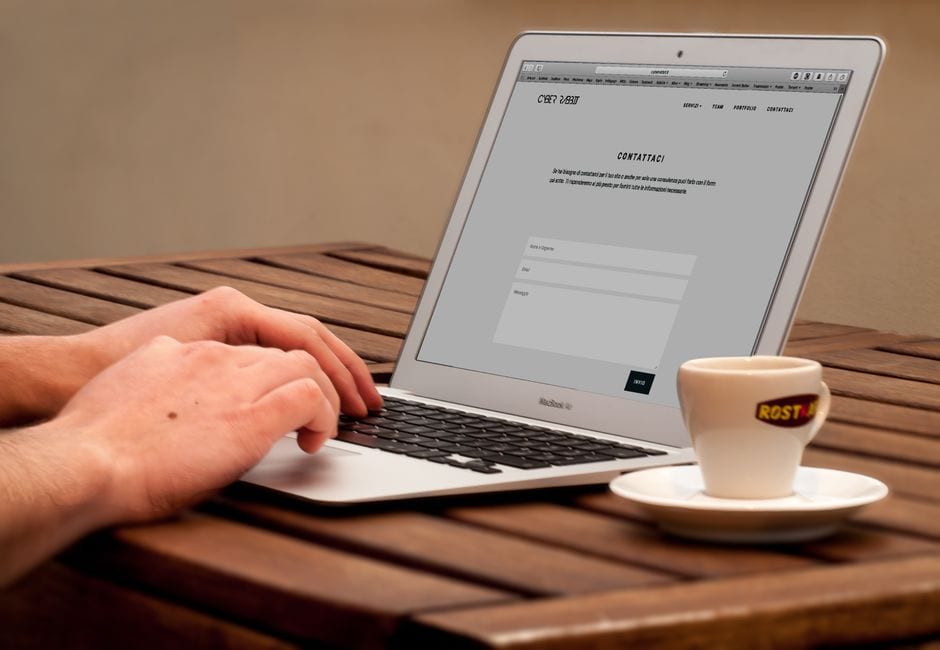 Illustrative stock photo of hands typing on a laptop beside coffee, not a featured local business.