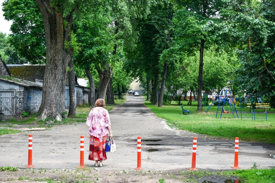 A person walking along a tree-lined park path near play equipment, illustrative stock photograph