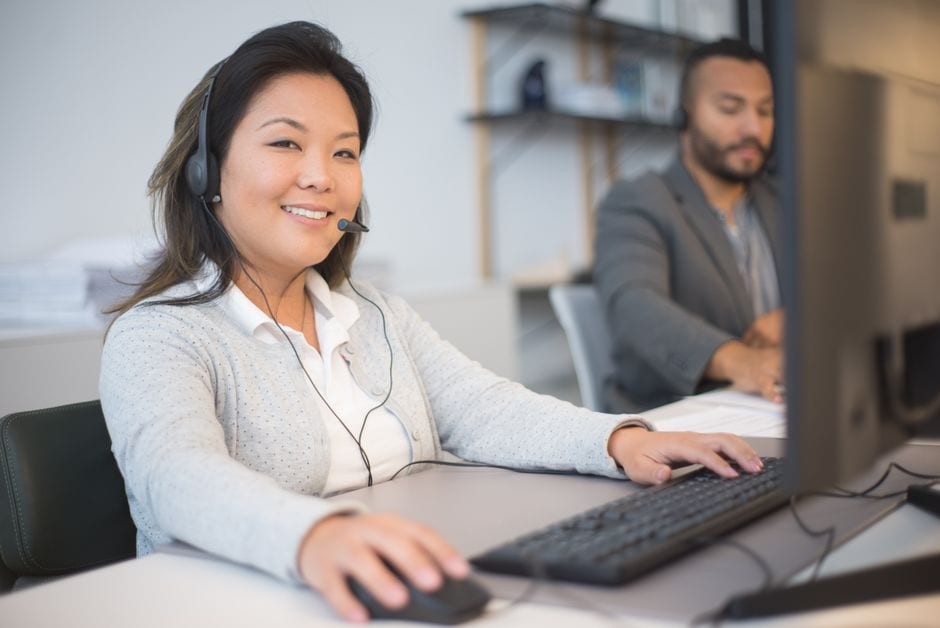 Illustrative stock photo of two customer service employees wearing headsets at computers