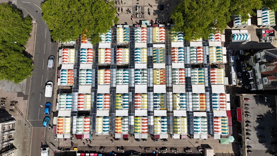 An overhead view of Norwich Market&rsquo;s rows of stalls with striped colourful roofs
