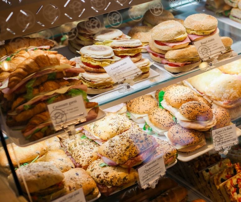Illustrative stock photo of sandwiches and bagels in a bakery display, not Art Mart products or premises.